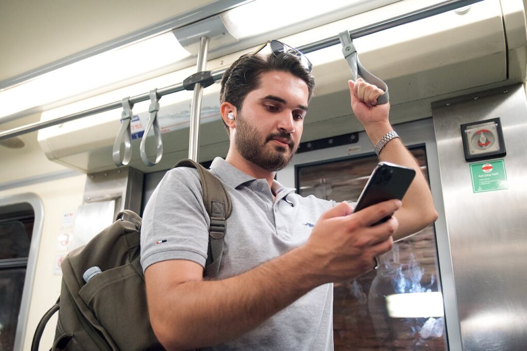Man Travelling on Train With Phone